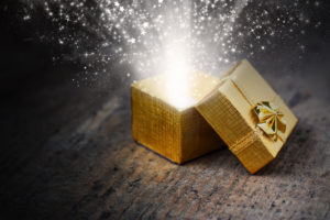 Open magic gift with rays and sparks close-up on a wooden surface